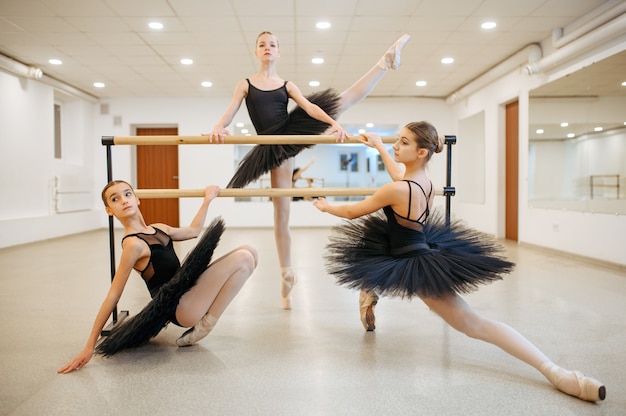 Eleganckie baleriny nastolatki pozują przy barze w klasie. Szkoła baletowa, tancerki na lekcji choreografii, dziewczyny ćwiczące taniec gracji