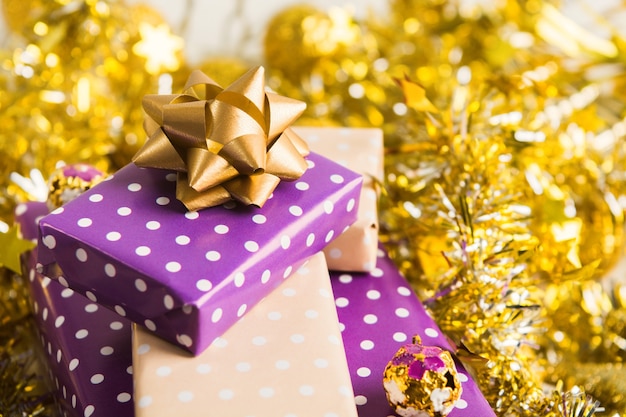 Eleganckie beżowo-fioletowe pudełka na prezenty układają się w stos ze wstążką ze złotą dekoracją świąteczną