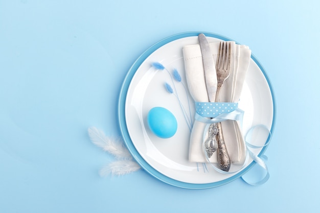 Eleganckie stylowe nakrycie stołu. Nóż i widelec na serwetce na talerzu na niebieskiej powierzchni.