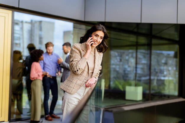 Elegantna bizneswoman zaangażowana w rozmowę telefoniczną przed nowoczesnym budynkiem biurowym