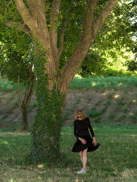 Zdjęcie elegantna starsza dama ubrana na czarno relaksująca się w parku wiosną