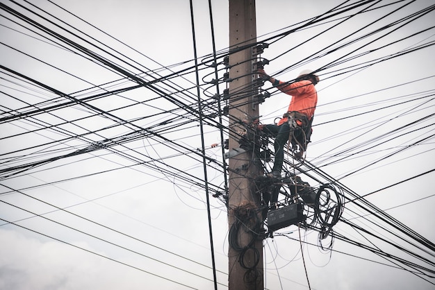 Elektrycy Wspinają Się Po Słupach Elektrycznych, Aby Instalować I Naprawiać Linie Energetyczne.