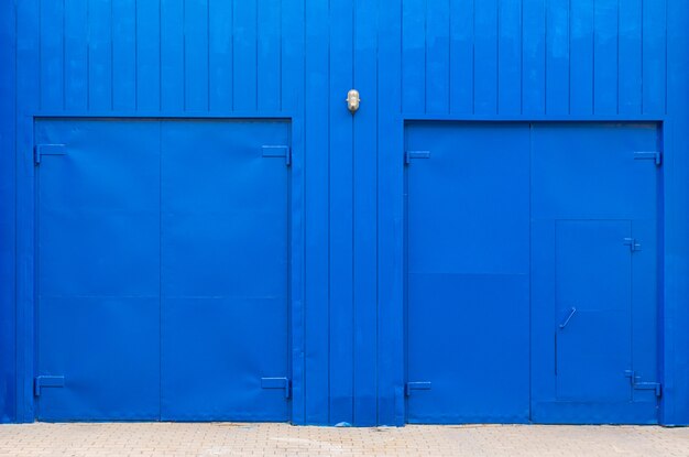 Elektryczne niebieskie ściany z drewnianymi deskami i szerokie niebieskie drzwi.