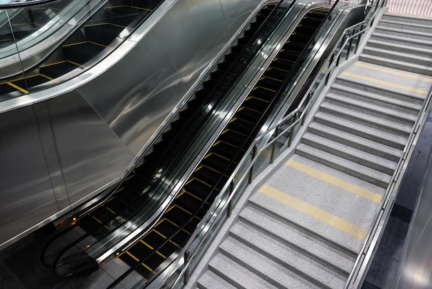 Elektryczne schody ruchome i zwykłe klatki schodowe na stacji metra. Łatwy i wygodny chodnik w centrum handlowym, centrum handlowym, placu, terminalu lotniska lub metrze.