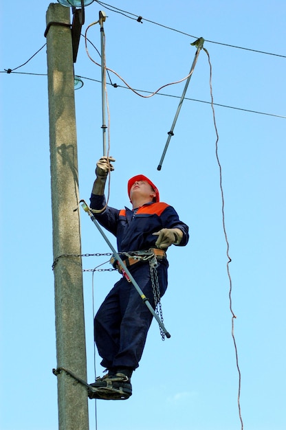 Elektryk instaluje uziemienie na linii energetycznej przed jej naprawą.