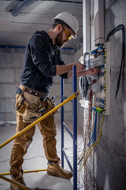 Elektryk mężczyzna pracuje w rozdzielnicy z elektrycznym kablem połączeniowym.