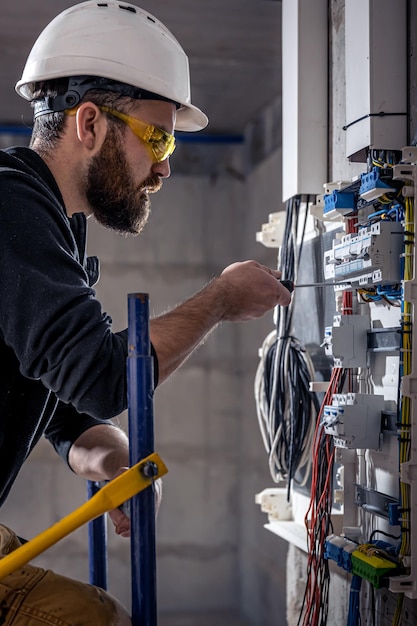 Elektryk mężczyzna pracuje w rozdzielnicy z elektrycznym kablem połączeniowym