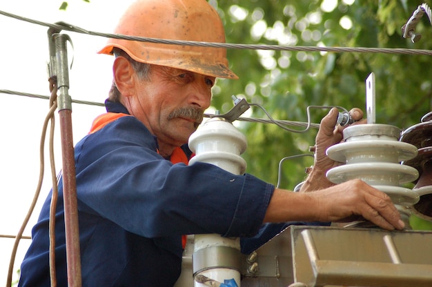 Elektryk na elektrycznej szafie sterowniczej wymienia uszkodzony izolator.