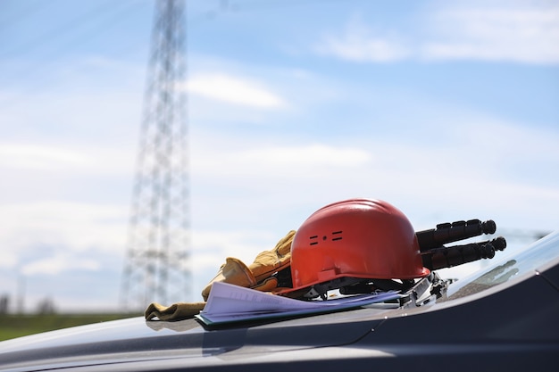 Elektryk Na Polach W Pobliżu Linii Elektroenergetycznej. Elektryk Zarządza Procesem Wznoszenia Linii Energetycznych. Mechanik W Kasku I Odblasku Tworzą Podczas Pracy Specjalne Rękawiczki.