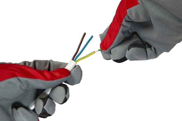 Elektryk usuwa izolację z trójrdzeniowego drutu miedzianego Ręce w rękawice ochronne i kabel elektryczny na białym tle