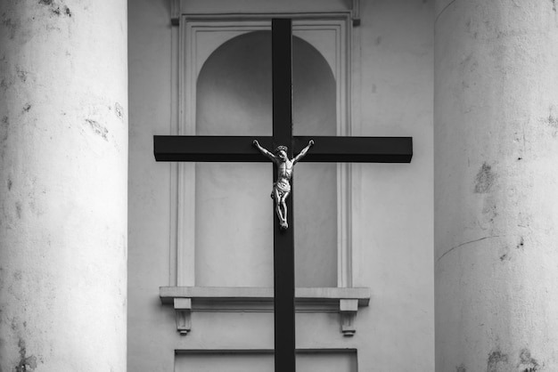 Element zewnętrza kościoła katolickiego Czarno-biały krzyż z krucyfiksem pomiędzy białymi kolumnami