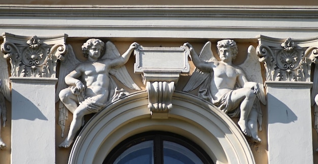 Elementy architektury klasycznej z dwoma rzeźbami aniołów nad drzwiami wejściowymi