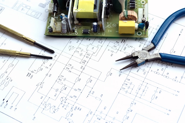 Elementy elektryczne i narzędzia precyzyjne leżące na rysunku konstrukcyjnym elektroniki