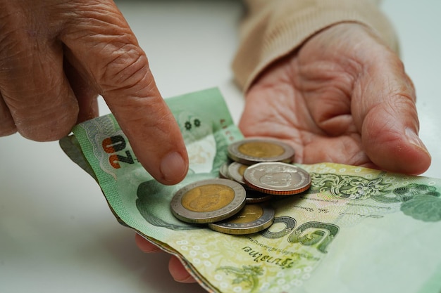 Emerytowana starsza kobieta liczy monety i martwi się o miesięczne wydatki i opłatę za leczenie