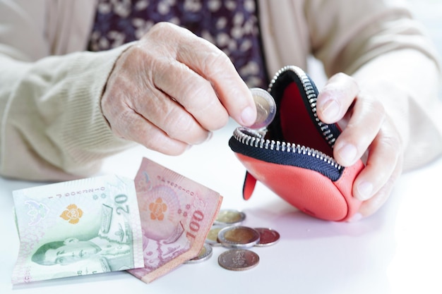 Emerytowana starsza kobieta liczy monety i martwi się o miesięczne wydatki i opłatę za leczenie