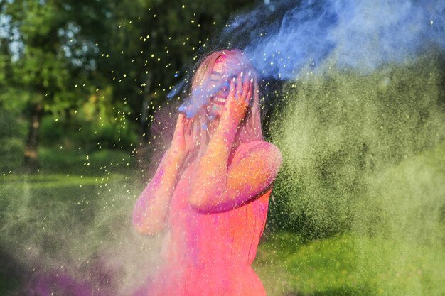 Emocjonalna blondynka z eksplodującą kolorową farbą świętuje święto Holi