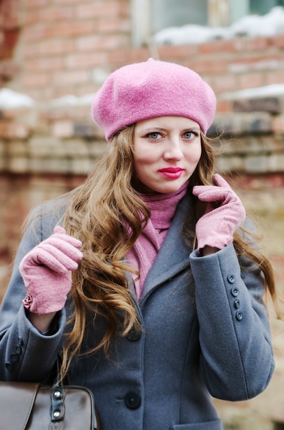Emocjonalna dziewczyna w szarym płaszczu i różowym berecie