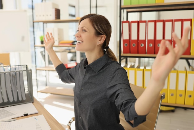 Emocjonalna kobieta czuje się szczęśliwa, kończąc projekt rozkładając ręce i uśmiechając się pracownicę