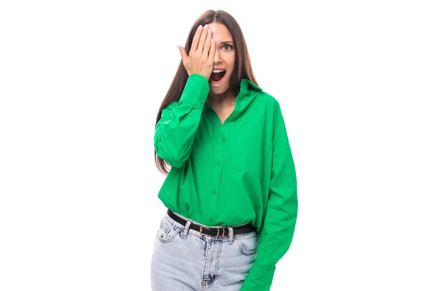 Emocjonalna młoda brązowooka brązowowłosa kobieta z jasnym wyrazem twarzy w zielonej bluzce na