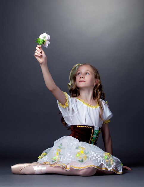 Emocjonalna tancerka baletowa pozująca patrząc na kwiat
