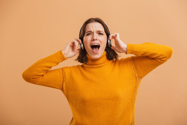 Emocjonalne piękna młoda kobieta słuchanie muzyki w słuchawkach śpiewających.