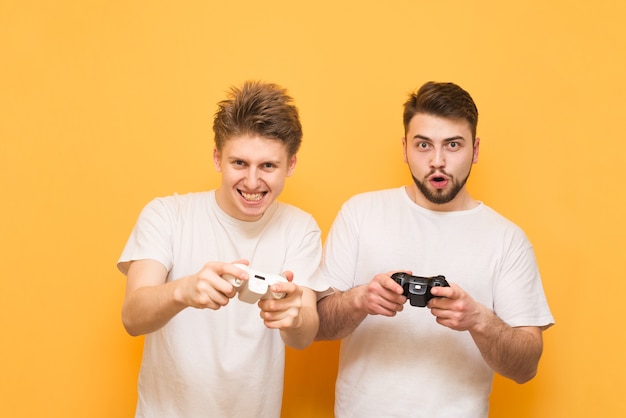 Zdjęcie emocjonalni gracze z gamepadem w dłoni, grający w gry wideo nastawione na żółty