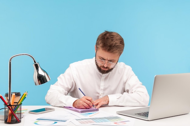 Emocjonalny biznesmen pracujący na laptopie na niebieskim tle