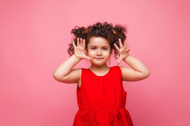 Emocjonalny portret dziewczynki w czerwonej sukience na różowym tle