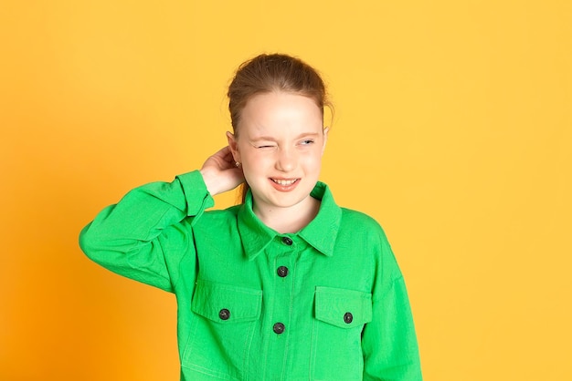 Emocjonalny portret roześmianej ślicznej dziewczynki w studio na żółtym tle emocje język migowy dziecko uśmiecha się i patrzy w kamerę i pokazuje emocje