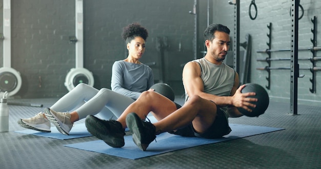 Zdjęcie energia fitness i przyjaciele na podłodze siłowni z piłką siłową do treningu siły i ćwiczenia razem cross workout i czarna kobieta z mężczyzną do sportu siły i kardio w siłę rdzenia i nastawienia