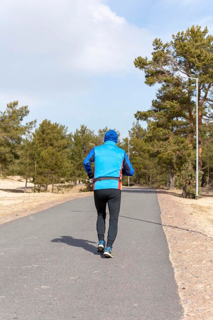 Energiczny, aktywny mężczyzna w sportowym stroju wybiera się na bieg po miejskim parku w słoneczny wiosenny poranek