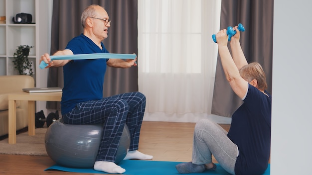 Energiczny Starszy Para Trening W Domu Przy Użyciu Hantli I Piłki Stabilności. Zdrowy Styl życia Osoby Starszej ćwiczenie W Domu, Trening I Trening, Aktywność Sportowa W Domu