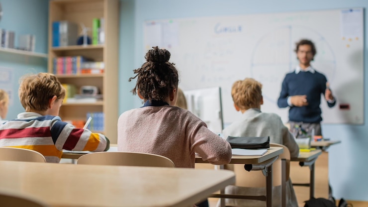 Zdjęcie entuzjastyczny nauczyciel wyjaśnia lekcje i zadaje pytania z klasy pełnej inteligentnych, zróżnicowanych dzieci w szkole podstawowej grupa inteligentnych, wieloetnicznych dzieci uczy się nauki i twórczego myślenia