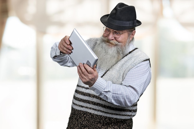 Zdjęcie entuzjastyczny starszy mężczyzna grający w gry online za pomocą cyfrowego tabletu stary mężczyzna grający w grę online rozmycie w...