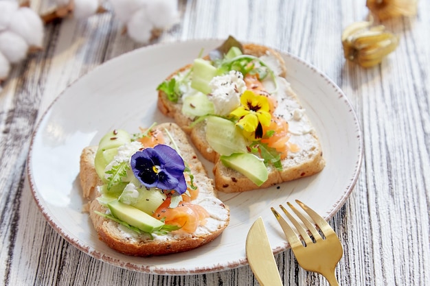 Estetyczne tosty z wędzonym łososiem, ogórkiem z awokado i jadalnymi kwiatami Dieta pescetarska Zdrowa przystawka