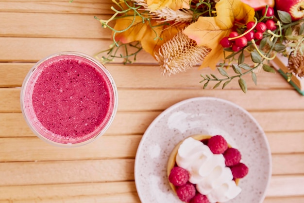 Estetyczny zdrowy jesienny lunch różowy koktajl truskawkowy i francuska tarta na drewnianym stole