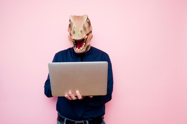 Zdjęcie euforyczny mężczyzna z głową dinozaura za pomocą laptopa