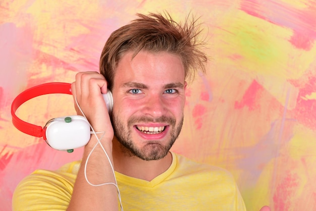 Europejczyk dobrze się bawi Niebieskooki stylowy hipster ze smartfonem Muzyczny styl życia Wesoły nastoletni dj słuchający piosenek przez słuchawki Amerykański przystojny brodaty facet ze słuchawkami