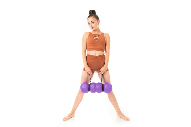 Europejska brunetki dziewczyna w brown sporta swimsuit z masaży stojakami na bielu
