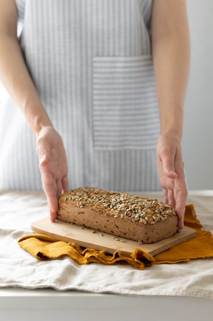 Europejska piekarz trzymający chleb gryczany biała kobieta w lekkim fartuchu trzymająca domowy zakwas
