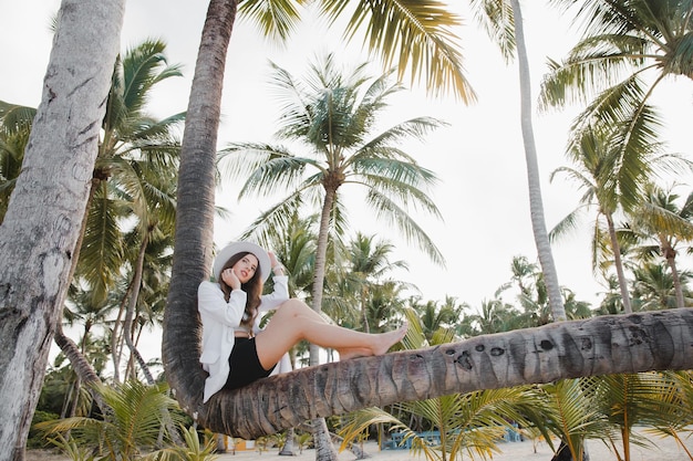 Europejska piękna szczęśliwa ciemnowłosa dziewczyna w pobliżu palmy kokosowej na białej, piaszczystej plaży