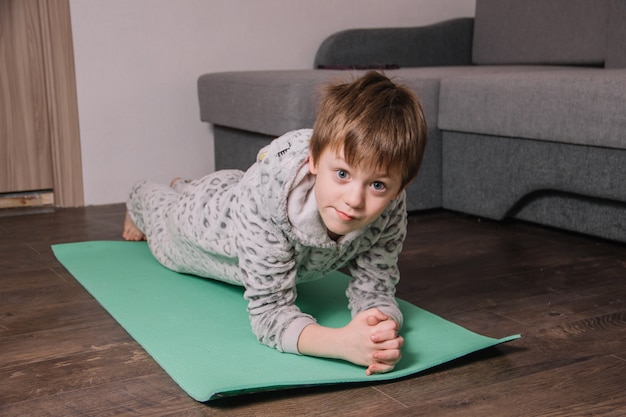 Zdjęcie europejskie dziecko w domu na dywanie wykonuje różne ćwiczenia sportowe w celu wzmocnienia odporności