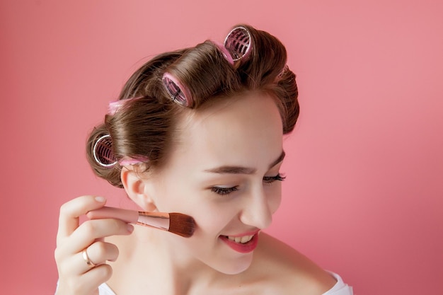 Eyeliner makijaż oczu pielęgnacja urody kobieta Dziewczyna oddanie koloru ołówka oczu na oczy patrząc w lusterko kieszonkowe uśmiechający się szczęśliwy na różowym tle