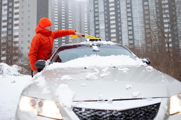 Facet czyści śnieg szczotką z samochodu Mężczyzna dba o samochód zimą