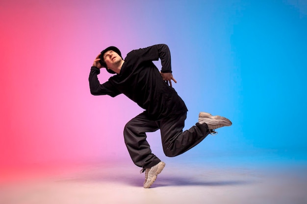 Facet hiphopowy wykonawca break dance w neonowym oświetleniu klubowym i wykonujący akrobatyczne sztuczki męskiego tancerza
