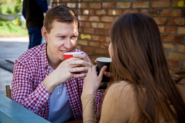 Facet i dziewczyna piją kawę w parku na tarasie w kawiarni