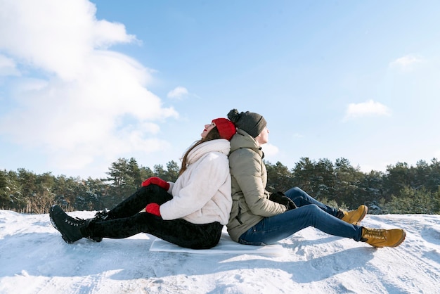 Facet i dziewczyna siedzą plecami do siebie na śniegu Mężczyzna i kobieta na zewnątrz