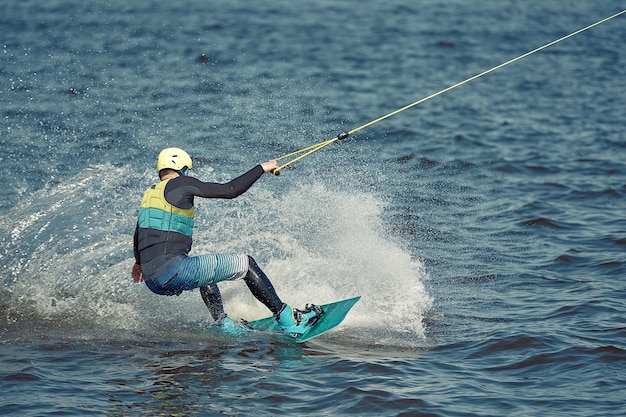 Facet jedzie na wakeboardzie po rzece. Sporty aktywne i ekstremalne.