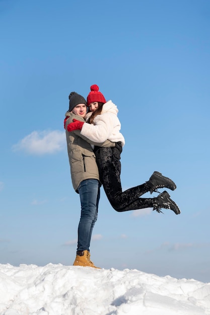 Facet podniósł swoją dziewczynę Szczęśliwa młoda para idzie w zimowy dzień Portret para zakochanych przeciw błękitne niebo