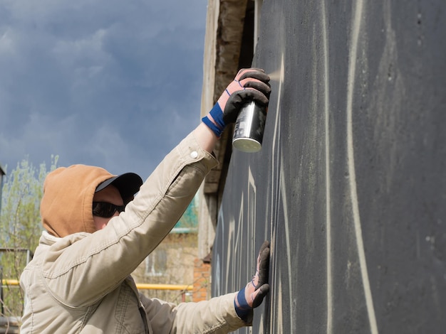 Zdjęcie facet w kapturze i czarnych okularach pisze graffiti